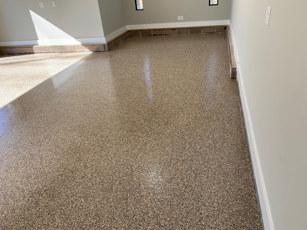 Residential garage interior with tan decorative flake epoxy concrete floor coating in Hillsboro OR