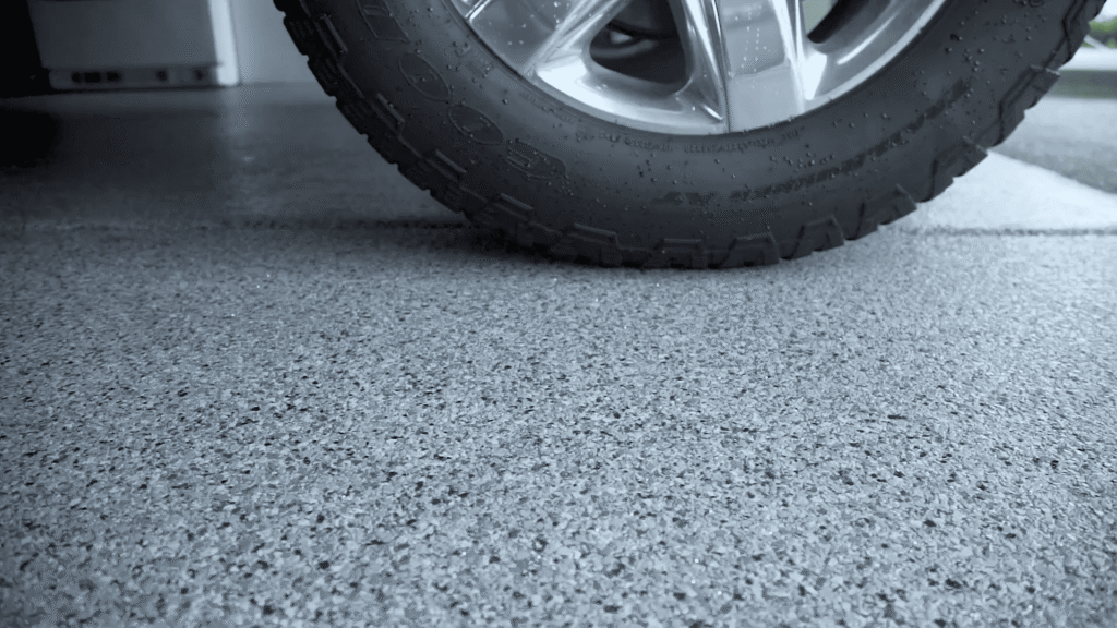 Vehicle tire parked on gray decorative flake epoxy garage floor coating