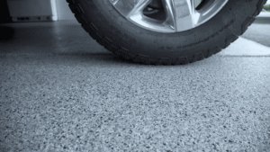 Vehicle tire parked on gray decorative flake epoxy garage floor coating